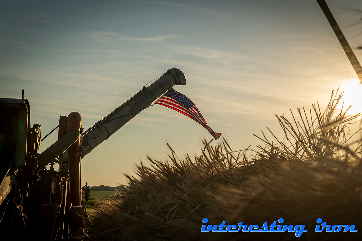 American flag waving near farm equipment at sunset