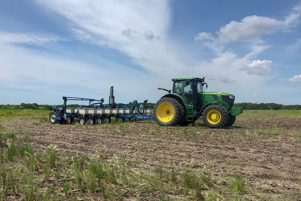 tractor pulling a kinze 3600 planter, field in foreground, sky with clouds